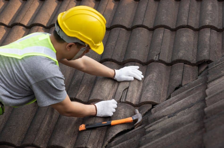 worker replacing old tile on roof
