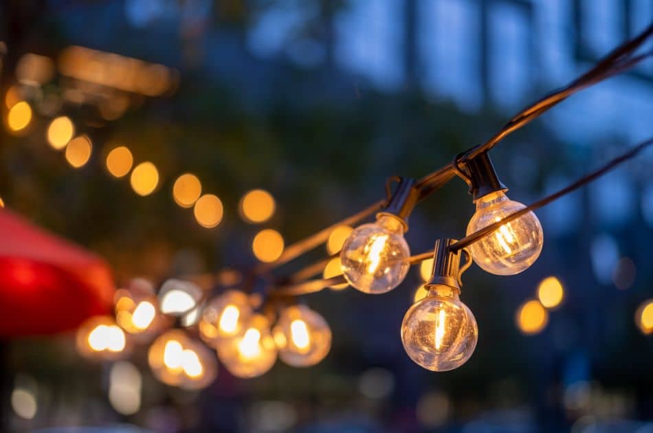 Close-up of illuminated string lights with multiple clear bulbs against a dusky evening sky.