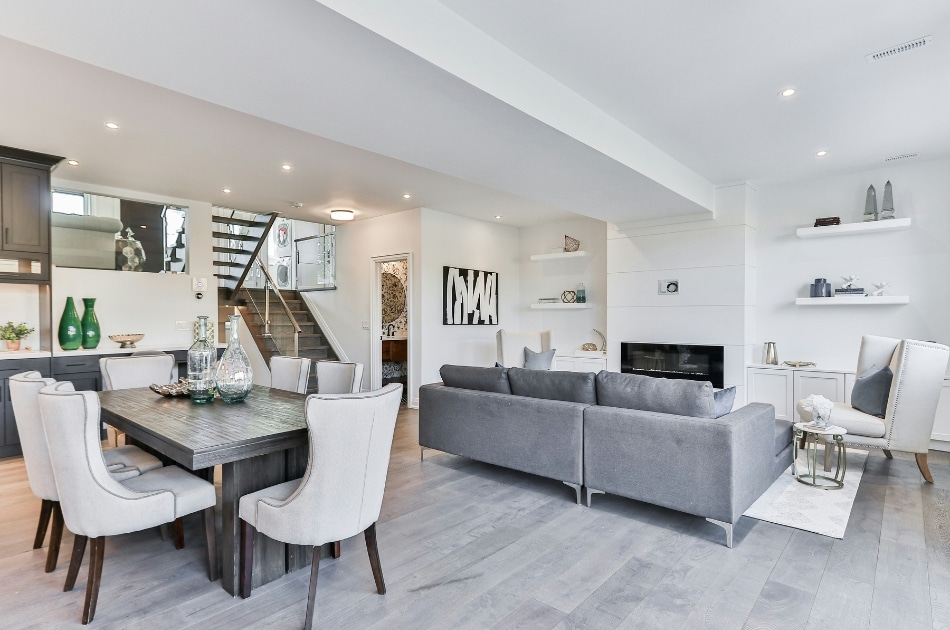 Inside of a home. White chairs at a table and a grey couch.