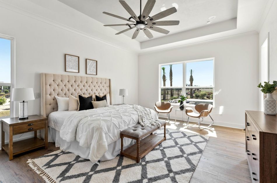 Bright bedroom with tufted headboard, large window, and seating area.